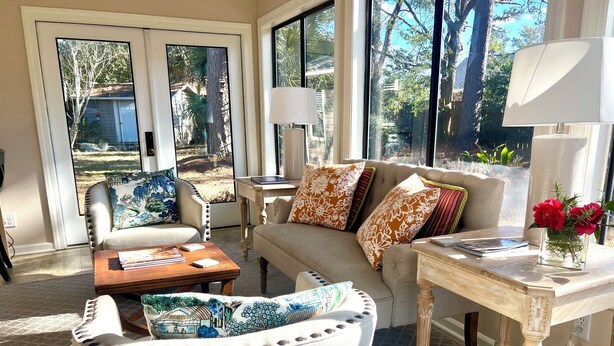 A spacious living room with a beige sofa, a wooden coffee table, and a small side table with a lamp.