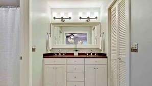 A bathroom with a vanity, a mirror, and a ceiling fan.