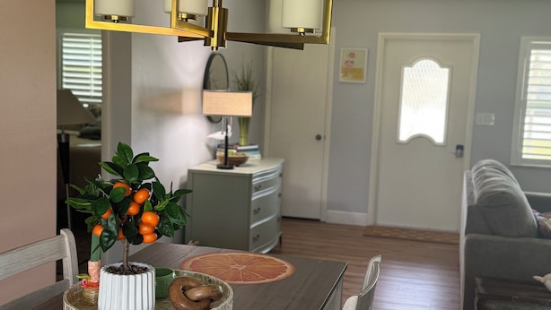 Ein Essbereich mit Holztisch, Stühlen, einer Kronleuchter und einem Blumentopf.