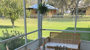 Ein überdachter Patio-Bereich mit Holzmöbeln und einem bunten Teppich.