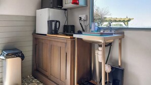 A compact kitchen with a microwave, coffee maker, and sink. A window provides a view of the outdoors. - 1 bedroom accommodation in Ormskirk (Ormskirk)
