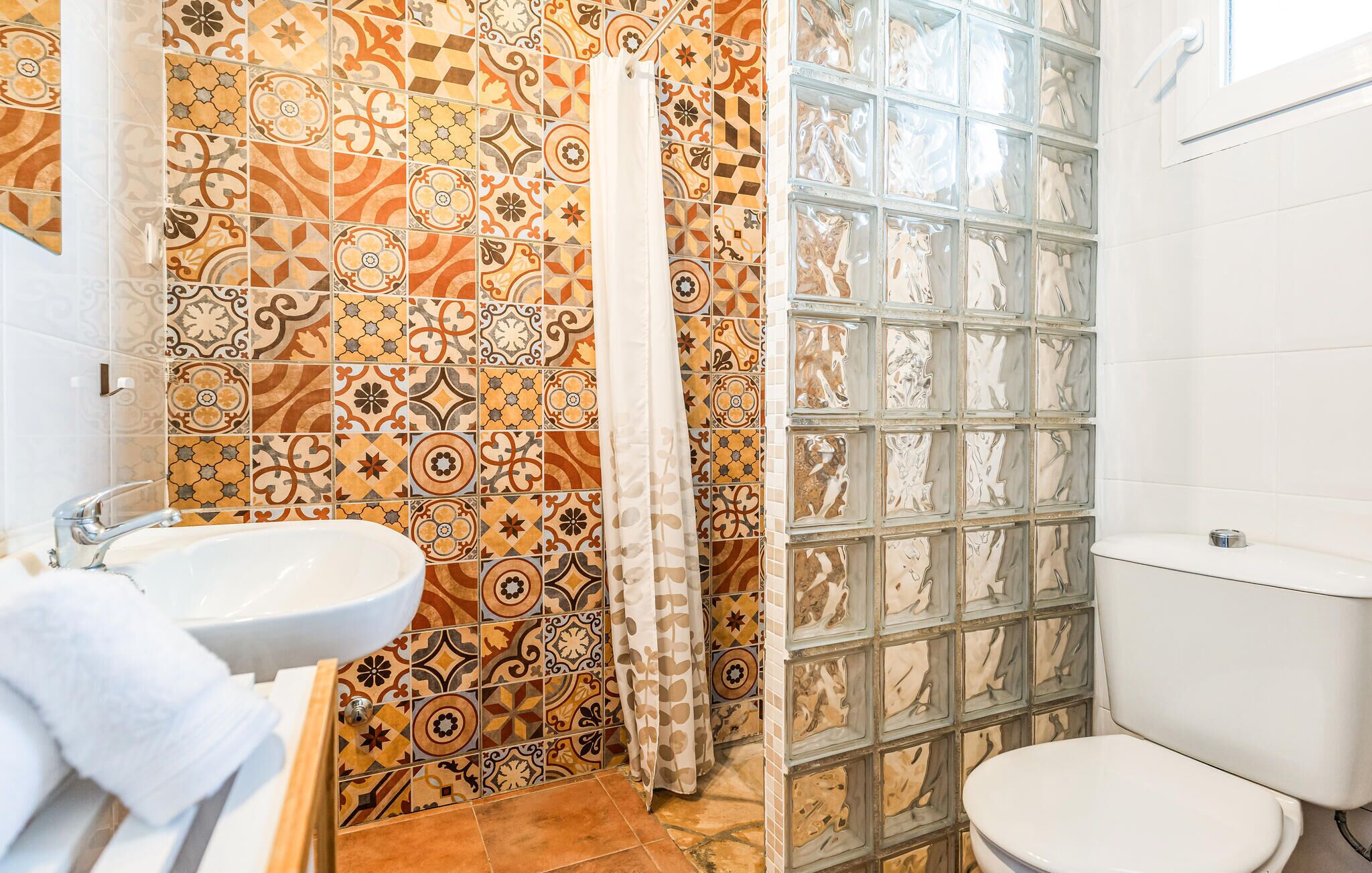 A bathroom with patterned tiles, a white sink, and a toilet.