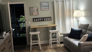 A cozy room with a desk, two stools, a couch, and a bed. - Cozy condotel with King Bed, WiFi, great pool, fitness room and much more! (Sarasota)