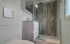 Bathroom features a glass-enclosed shower, pedestal sink, and wall-mounted light switch.
