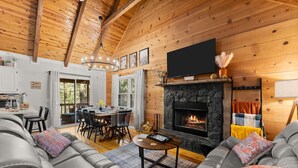 A cozy living room with a fireplace, leather sofas, and a dining area with natural light.