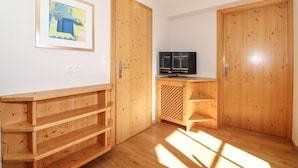 Een kamer met houten vloeren, een televisie op een houten dressoir en een schilderij aan de muur.