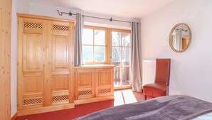 Een slaapkamer met een bed, een kledingkast, een stoel en een raam met gordijnen.