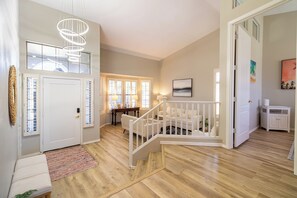 A spacious living area with a staircase, wooden flooring, and a view of the backyard. - Desert Oasis: 4BD/3BA- Pool/ 2 Living Rooms / Sleeps 8 (Mesa)