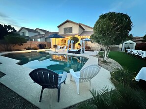 A backyard with a swimming pool, outdoor furniture, and a house in the background. - Desert Oasis: 4BD/3BA- Pool/ 2 Living Rooms / Sleeps 8 (Mesa)