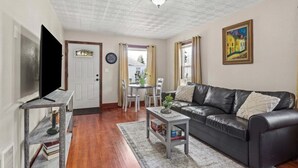 A living room with a black leather sofa, a coffee table, a TV, and a dining area with a table and chairs. - Charming Bungalow 1 Duplex in Lebanon. (Lebanon)