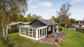 A house with a conservatory, a brick patio, and a garden. - Cozy home in Juelsminde with WiFi (Juelsminde)