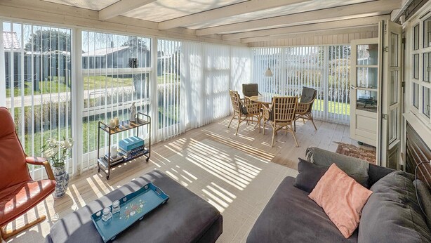 A sunroom with a sofa, a table, and chairs. - Cozy home in Juelsminde with WiFi (Juelsminde)