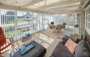 Uma sala de sol com sofá, mesa e cadeiras.