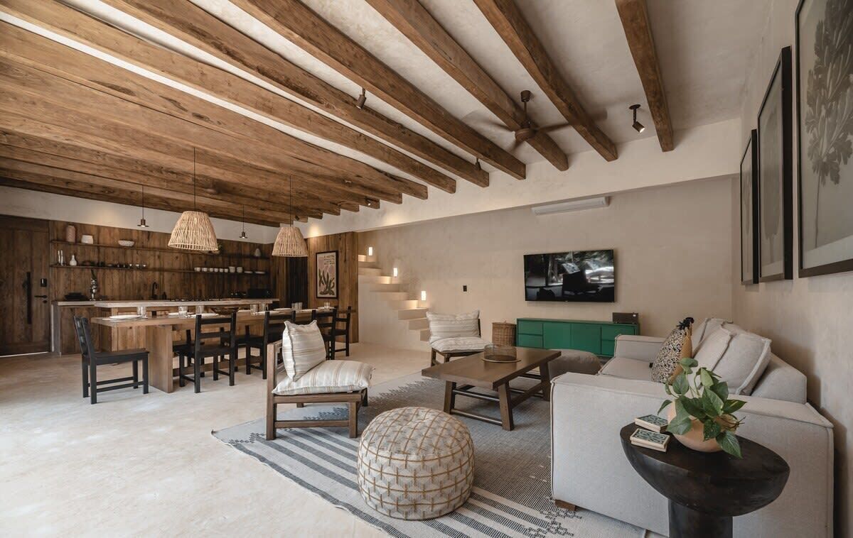 A spacious living area with a wooden ceiling, a dining table, sofas, and a television.