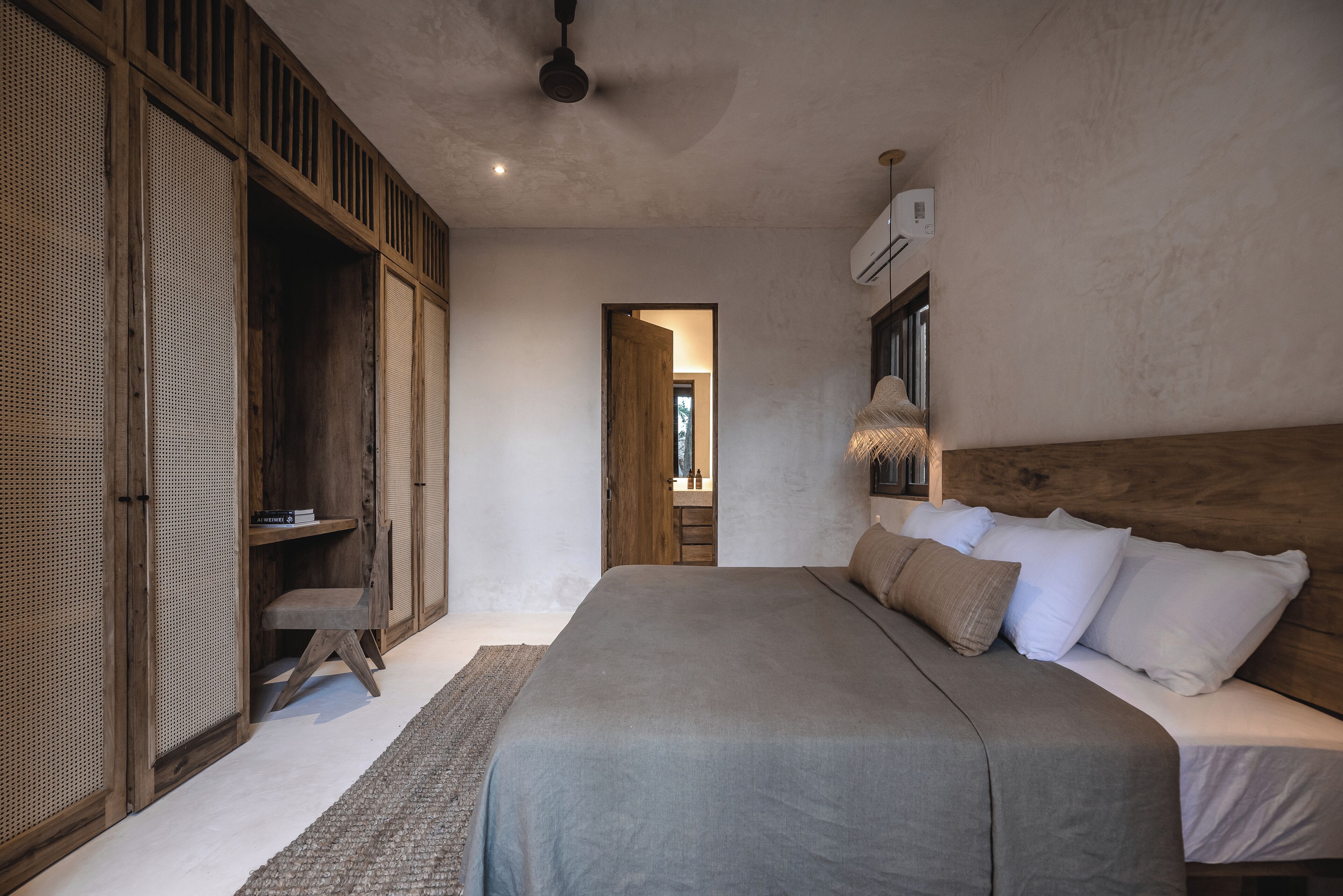 A bedroom with a large bed, wooden wardrobe, and a ceiling fan.