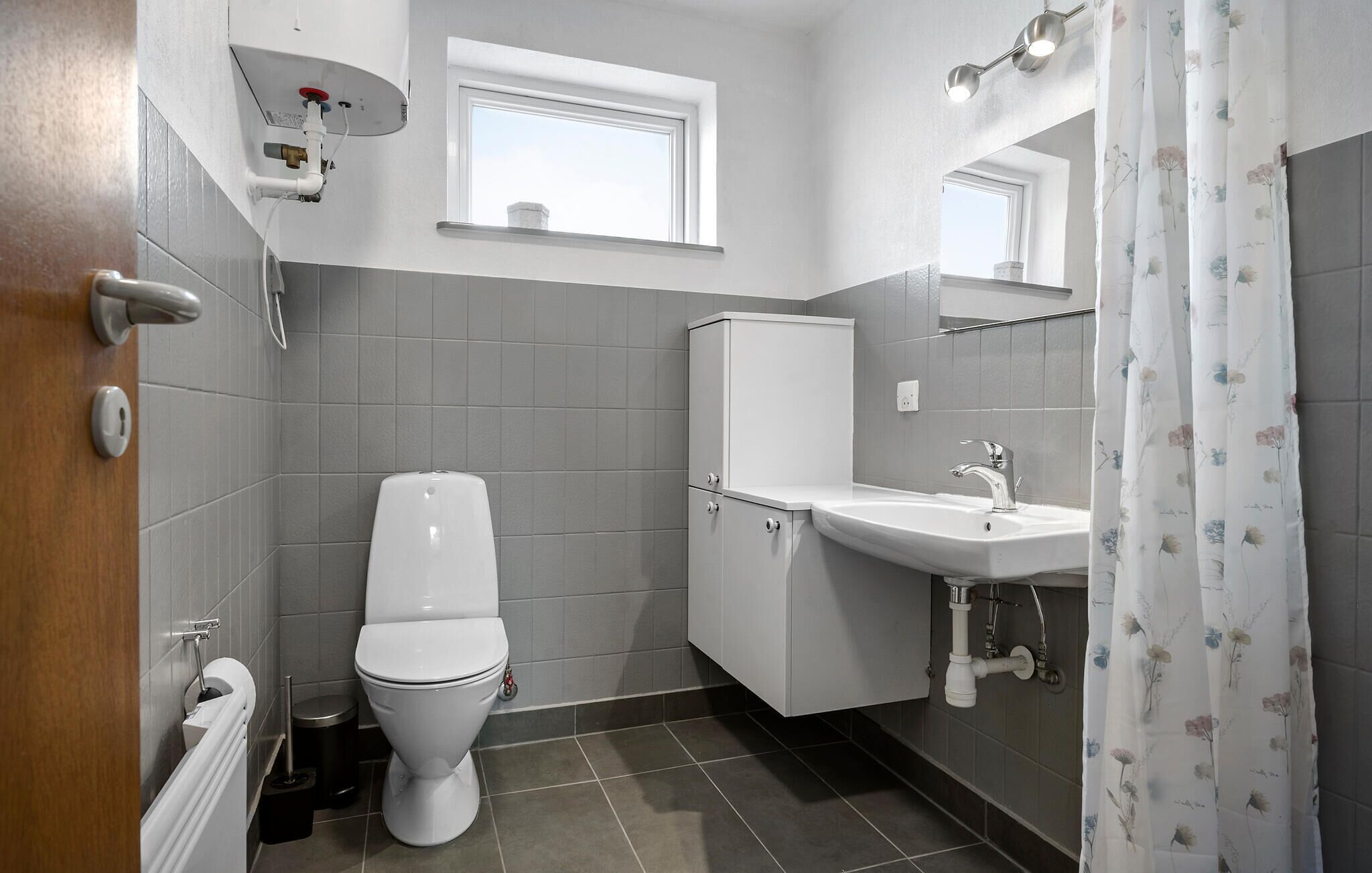 A modern bathroom with a toilet, sink, and shower curtain.