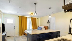 Una habitación de hotel pequeña con cama, escritorio, kitchenette y baño.