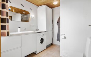 Ein kleines Badezimmer mit Waschbecken, Spiegel und Waschmaschine.