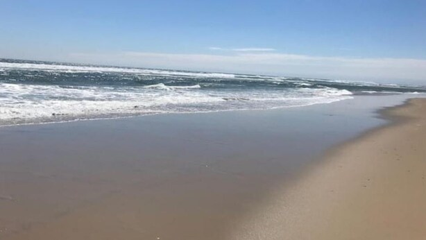 Una playa con olas y cielo despejado.