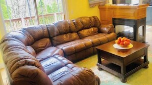 Una sala de estar con un sofá de cuero marrón, una mesa de centro de madera con frutas y una chimenea.