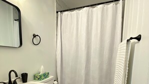 Ein Badezimmer mit Waschbecken, Toilette, Spiegel, Handtuchhalter und Duschvorhang.