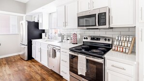 A modern kitchen with white cabinetry, stainless steel appliances, and a wooden floor. - Luxury Downtown Townhome w/ Private Garage Unit 6 (Cleveland)