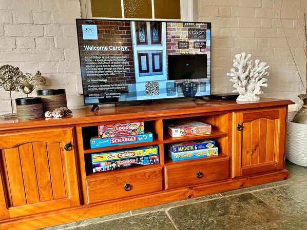 Un mueble de madera con centro de entretenimiento, un televisor mostrando un mensaje de bienvenida y un pronóstico del tiempo.