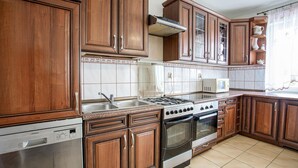 A kitchen with wooden cabinets, a stainless steel dishwasher, a stove, and an oven.