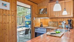 A wooden cabin kitchen with a dining area, wooden cabinets, a stove, and a sink.