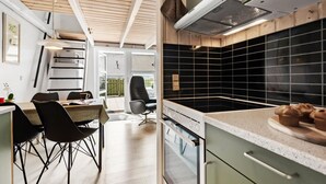 Une cuisine moderne avec un dosseret de carreaux noirs, un coin repas comprenant une table et des chaises, et une vue sur l’extérieur grâce à une porte vitrée.