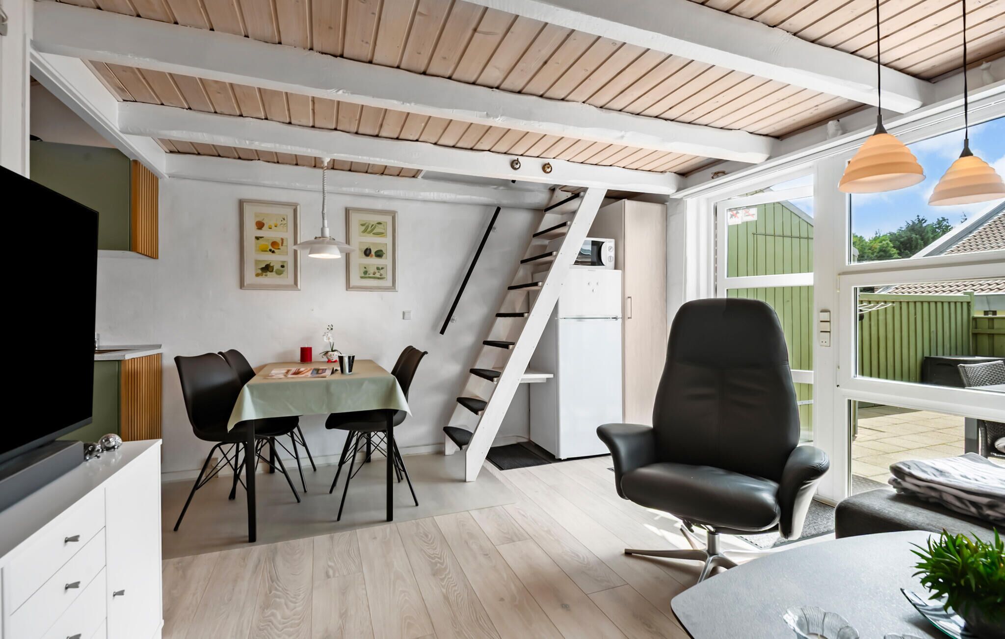A modern kitchen with a wooden ceiling, a dining area with a table and chairs, and a black office chair.