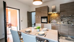 A modern kitchen with dark wood cabinets, a stone backsplash, and a dining area with wicker chairs and a table set for four.