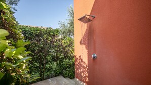 A garden with a showerhead mounted on a wall, surrounded by lush greenery.
