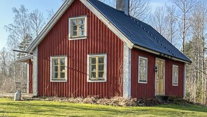 Een rood houten huis met een puntige dak en twee ramen.