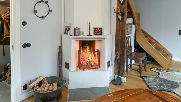 Een gezellige woonkamer met een open haard, een houten trap en een rustieke inrichting.