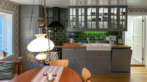 Een keuken met een houten tafel, een hanglamp en een groene tegelachtergrond.