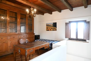 Une pièce comprenant une table à manger en bois, un lustre, une grande armoire et un tableau accroché au mur.