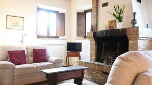 Uma sala de estar com sofá, mesa de centro, lareira e televisão.