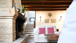 Uma sala de estar com lareira, sofá e escada que leva ao andar superior.