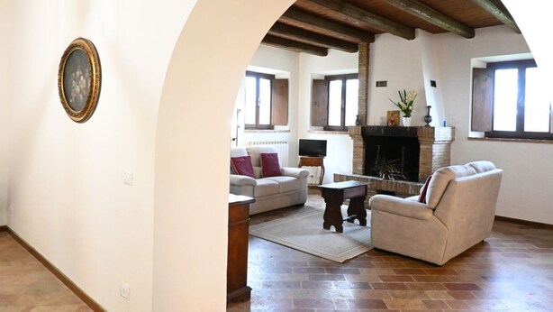 Uma sala de estar com lareira, sofá, mesa de centro e televisão.