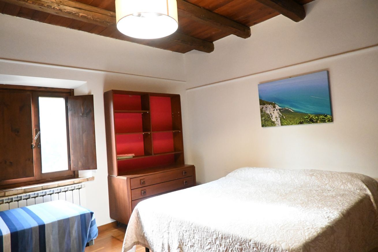 Une chambre à coucher avec un lit, une armoire en bois, un radiateur et une fenêtre.