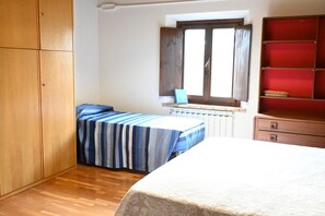 Um quarto com cama, janela, radiador e armário.