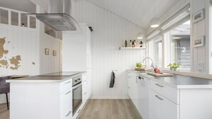 A modern kitchen with white cabinetry, a built-in oven, and a window above the sink.