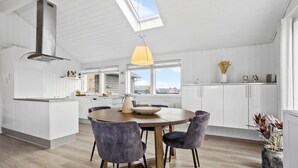 A modern kitchen with white cabinetry, a round wooden table, and four chairs.