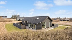 A modern house with a sloped roof, large windows, and a deck.