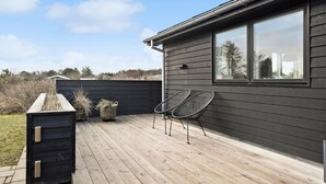 A wooden deck with two metal chairs and a small planter.