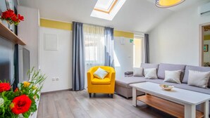 A modern living room with a yellow armchair, a grey sofa, and a white coffee table. There is a skylight above the sofa and a window with curtains. - Lovely apartment in Veli Brgud with WiFi (Veli Brgud)