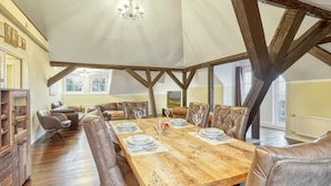 Un coin repas avec une table en bois dressée pour quatre personnes, entourée de chaises en cuir.