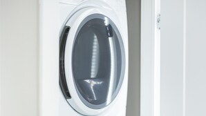 Lavadora y secadora apiladas en un espacio interior blanco.
