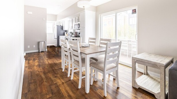 Una cocina luminosa con armarios blancos, una mesa de comedor de madera y sillas.